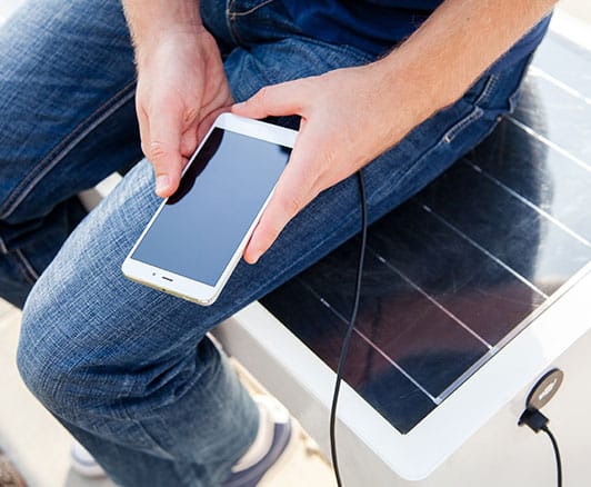Person charging their phone from a solar powered charging bench